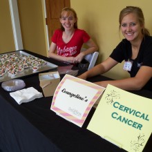 Volunteers smile from behind a table featuring chocolate covered strawberries from Evangeline's and information about cervical cancer