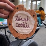 A hand holds a felt cookie with the words "tough cookie"