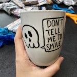 A hand holds a mug with the words "Don't tell me to smile"