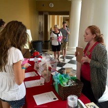 A guest and volunteer speak at the silent auction table