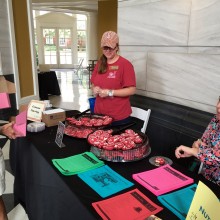 A guest visits a table featuring crimson football helmet cookies and information about nutrition