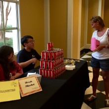 Guests speak with volunteers at a table featuring chocolate milk, sponsored by The Fresh Market